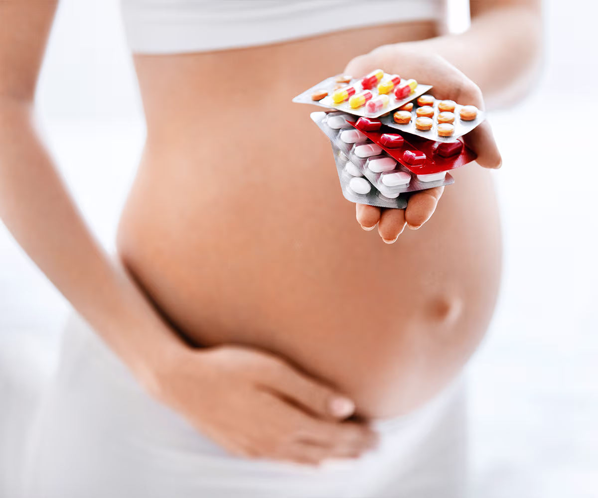 Safe Medications During Pregnancy photo showing a pregnant woman with a hand full of pills